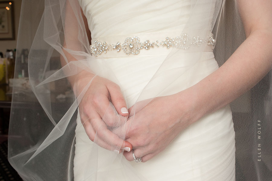 photo of the brides hands, embellished sash, and veil